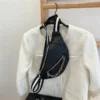 A black crossbody bag hanging on the wall