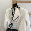 A white jacket on a hanger with a white chain bag